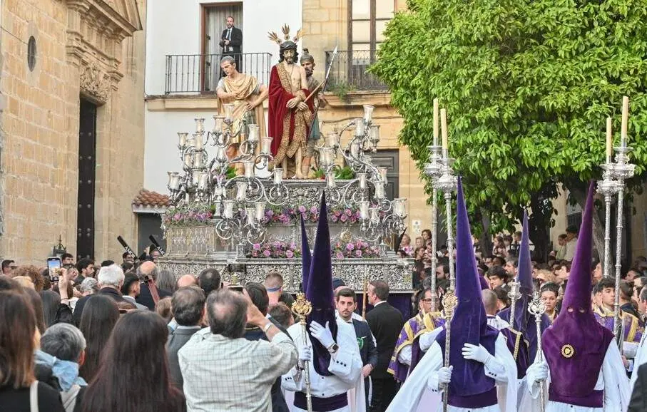  El paso del Se&ntilde;or del Ecce Homo, precedido por su cortejo de nazarenos de antifaz de terciopelo morado y t&uacute;nica y capa blancas. | Viva Jerez. 