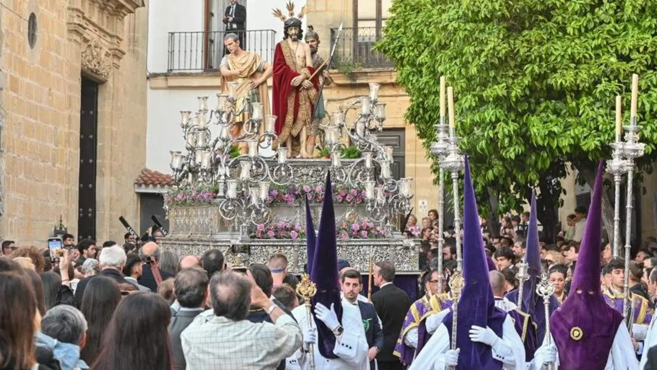  El paso del Se&ntilde;or del Ecce Homo, precedido por su cortejo de nazarenos de antifaz de terciopelo morado y t&uacute;nica y capa blancas. | Viva Jerez. 